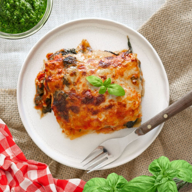 Gluten-free vegetarian lasagne with pesto and beans on plate, layered with vegetables and pasta.