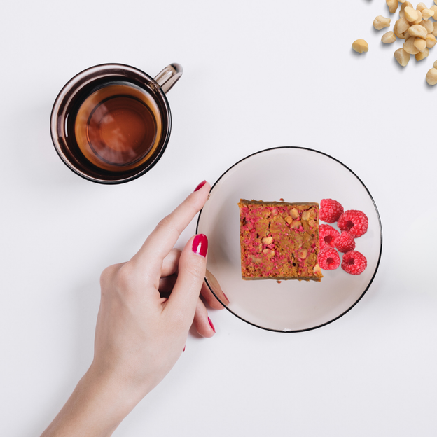 Delicious gluten-free, Low FODMAP raspberry and macadamia square with a up of tea.
