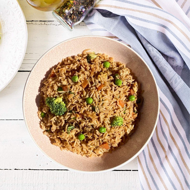 A bowl of gluten free, Low FODMAP, Vegetarian Fried Rice with Tofu, containing pieces of broccoli, carrot, and peas, served in a bowl.