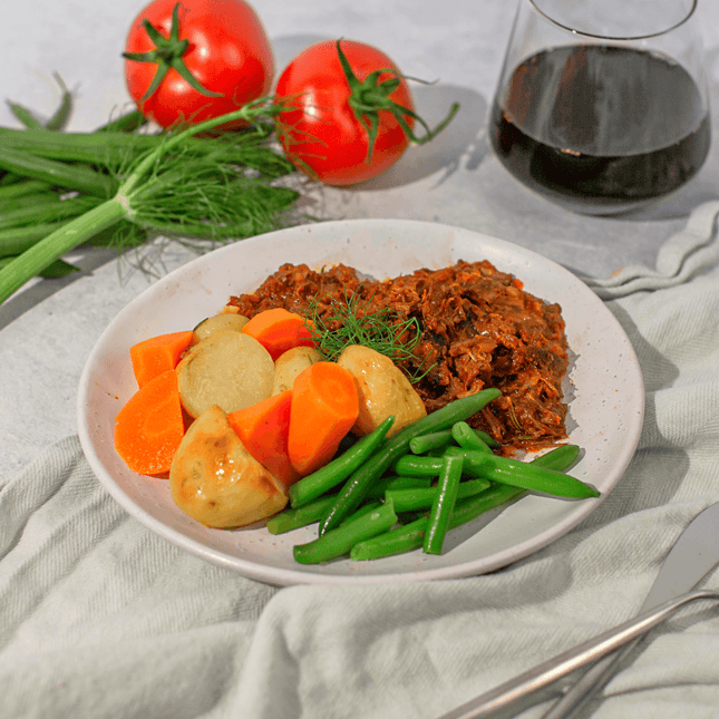 Beef & Bacon Stew w/ Roasted Veggies on a plate with glass of wine. Meal is Gluten Free, Lactose Free and Low FODMAP. 